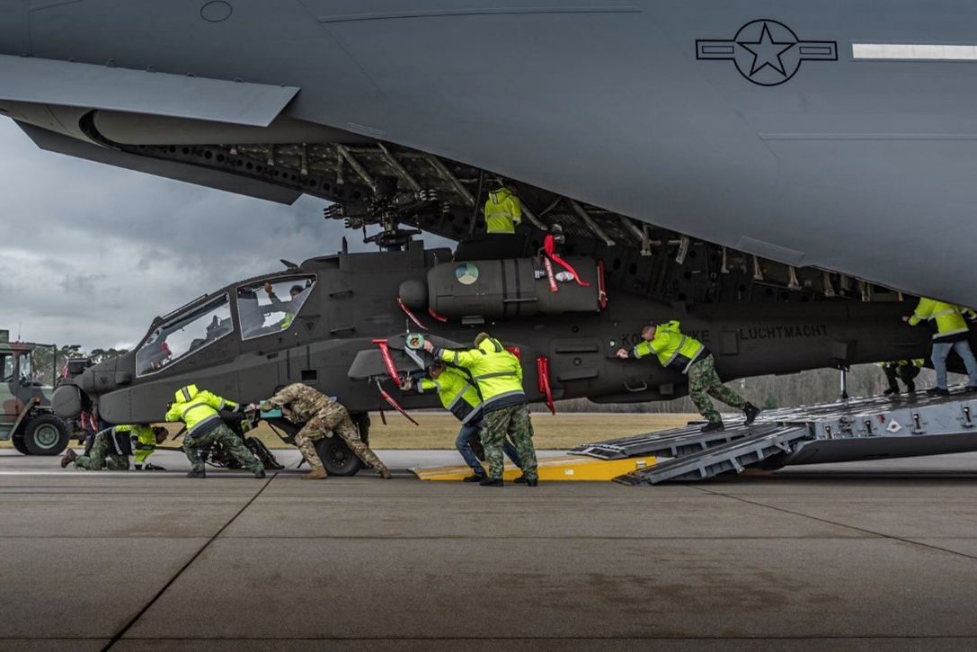 Get to the Chopper. U.S. airmen offload an AH-64 Apache helicopter assigned to the Royal Netherlands Air Force from an Air Force C-17 Globemaster III aircraft in an undisclosed location.